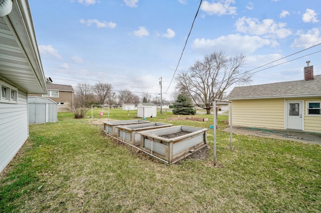view of yard featuring an outdoor structure, a storage unit, and a vegetable garden