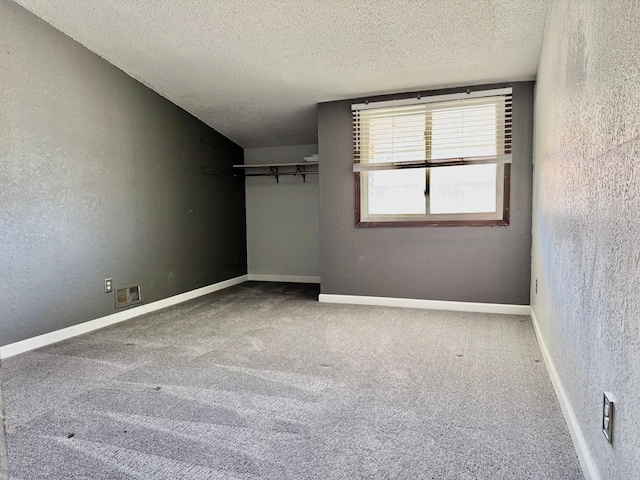 unfurnished bedroom with a textured ceiling, carpet flooring, a closet, a textured wall, and baseboards