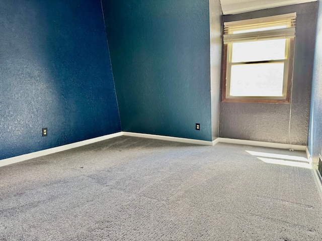 unfurnished room featuring a textured wall, carpet flooring, and baseboards