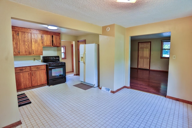 W340 State Road 29, Spring Valley, WI 54767 - kitchen with white refrigerator with ice dispenser, black gas range oven, brown cabinets, light countertops, and a textured ceiling
