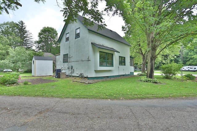 W340 State Road 29, Spring Valley, WI 54767 - view of side of property featuring a storage unit, stucco siding, a yard, and a shingled roof