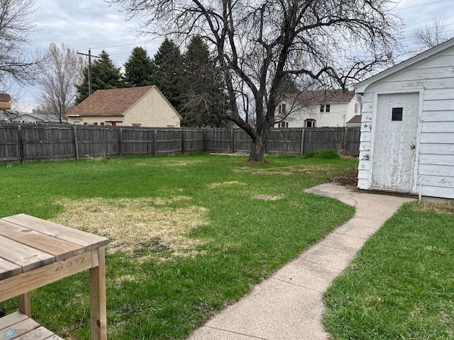 view of yard with a fenced backyard, a shed, and an outbuilding