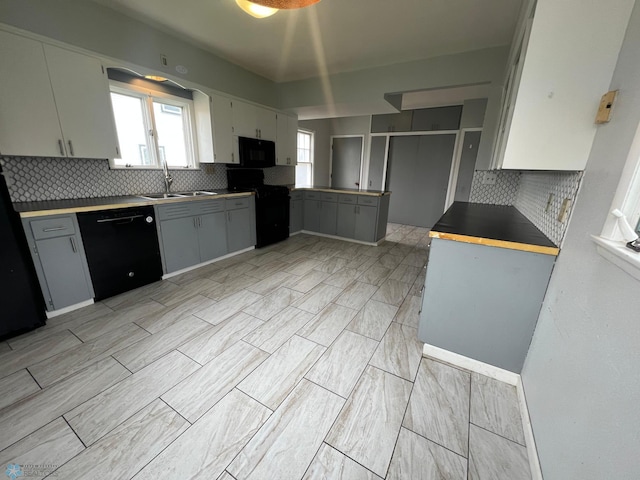 kitchen with gray cabinets, a sink, decorative backsplash, and black appliances