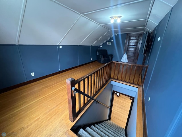 stairway featuring wood finished floors and lofted ceiling