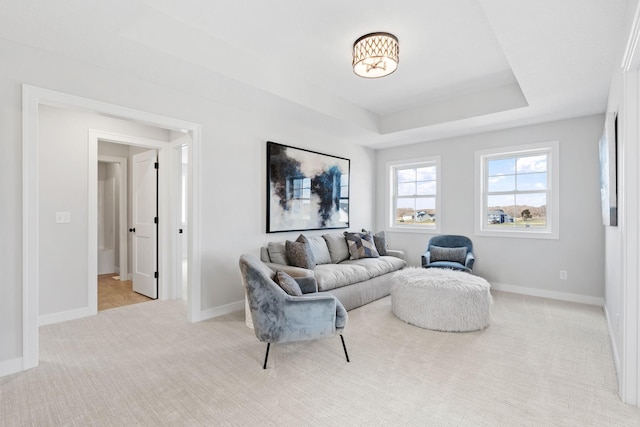carpeted living room with baseboards and a raised ceiling