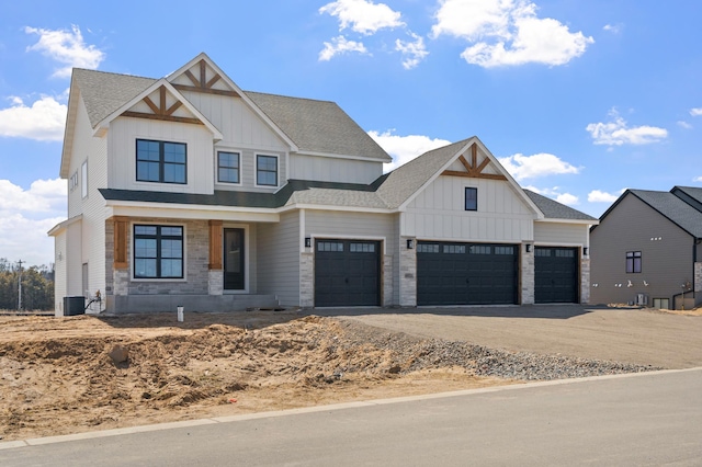 view of front of home featuring central air condition unit, concrete driveway, board and batten siding, an attached garage, and stone siding