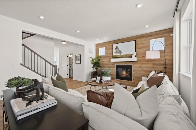 19321 Colonial Trl, Farmington, MN 55024 - living room with wooden walls, an accent wall, light wood-style flooring, recessed lighting, and a glass covered fireplace