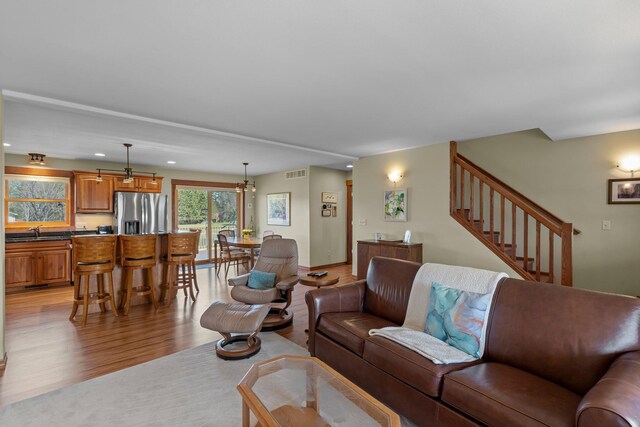 living room with visible vents, stairway, recessed lighting, light wood-type flooring, and a notable chandelier