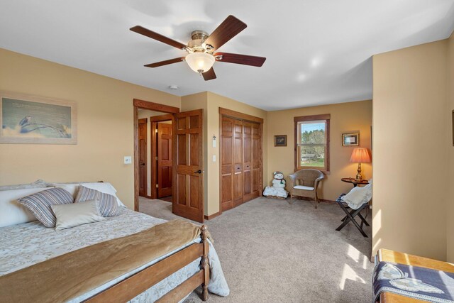 bedroom with ceiling fan, light colored carpet, baseboards, and a closet