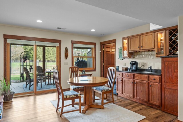 dining space featuring recessed lighting, visible vents, bar area, and wood finished floors