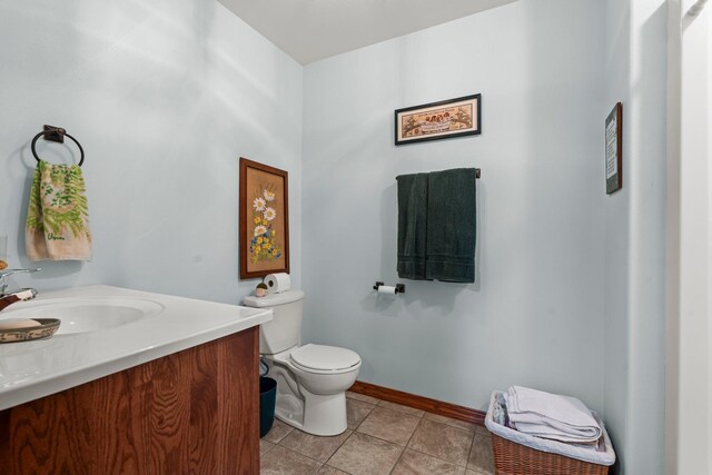 half bath featuring vanity, baseboards, tile patterned flooring, and toilet