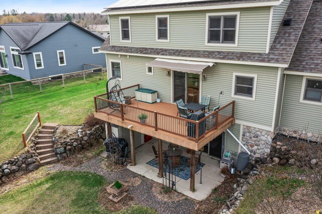 back of property featuring a patio, a shingled roof, a yard, and a deck
