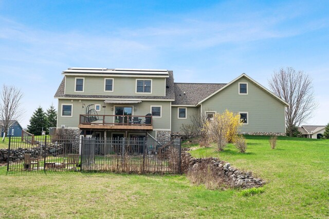 back of house with a lawn, a deck, fence, and roof with shingles