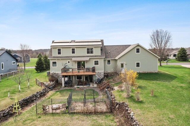 back of house featuring stone siding, a deck, a patio area, a lawn, and stairway