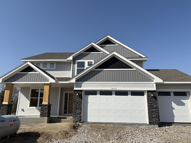craftsman house with an attached garage, a porch, stone siding, and dirt driveway