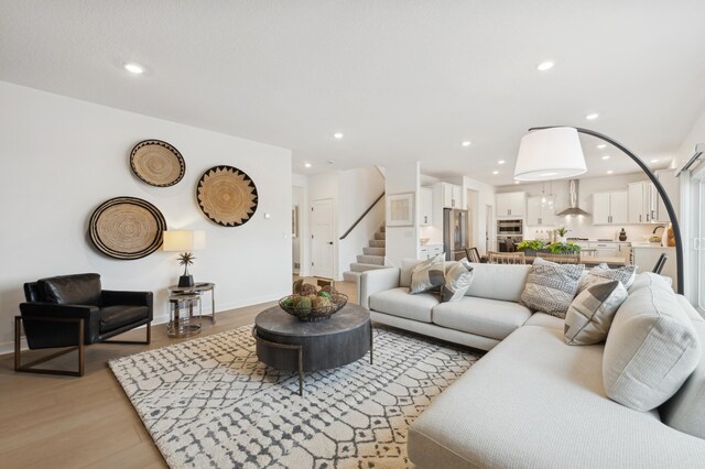 living room with recessed lighting, light wood-style floors, stairway, and baseboards