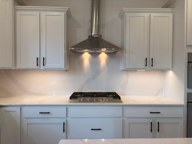 kitchen featuring stainless steel gas stovetop, decorative backsplash, light countertops, and wall chimney range hood