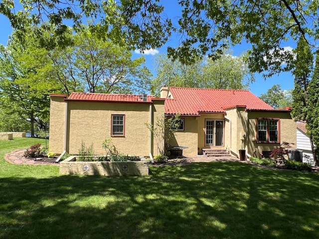 1260 Como Blvd E, Saint Paul, MN 55117 - rear view of house featuring entry steps, stucco siding, a tile roof, and a lawn
