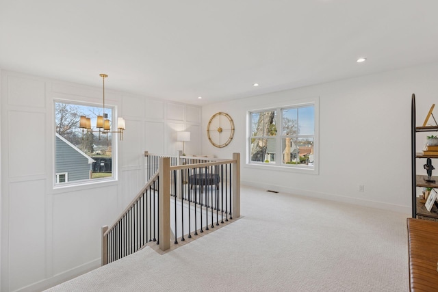 corridor with an upstairs landing, healthy amount of natural light, carpet, recessed lighting, and a chandelier