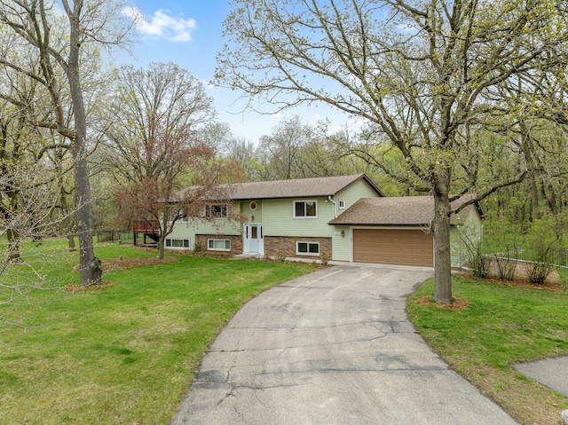 split foyer home featuring aphalt driveway, a garage, and a front lawn