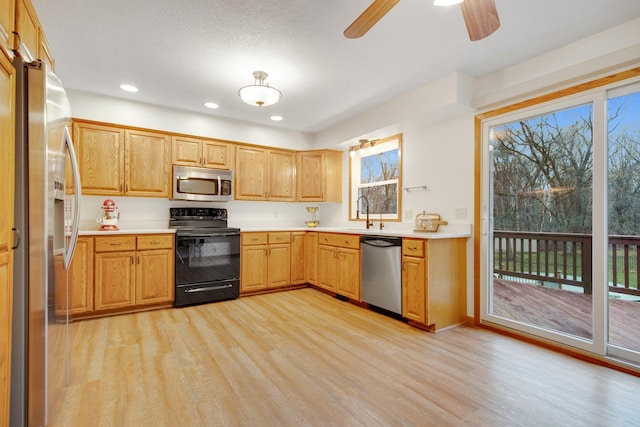 kitchen featuring a healthy amount of sunlight, light wood-style floors, stainless steel appliances, and light countertops