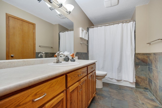 bathroom with shower / bath combo with shower curtain, vanity, toilet, and stone finish flooring