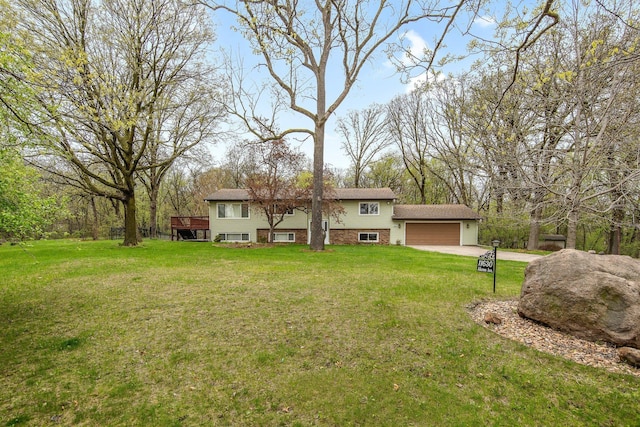 rear view of house with a yard, a garage, brick siding, and driveway