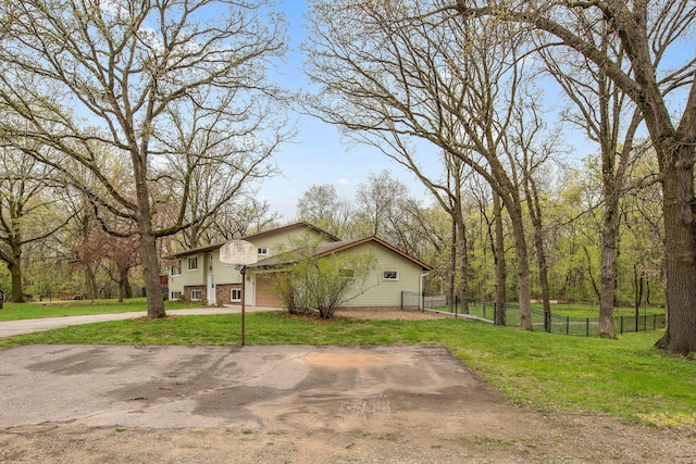 view of home's exterior featuring driveway, fence, and a lawn