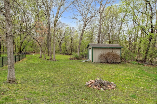 view of yard with an outbuilding, a shed, a fire pit, and fence