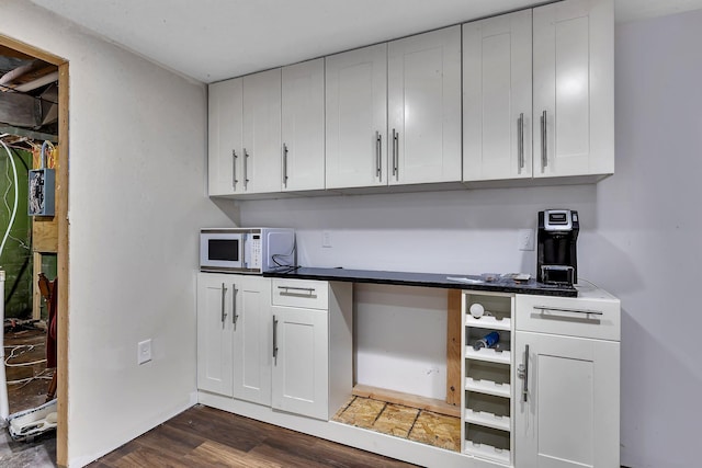 2021 6th St SW, Willmar, MN 56201 - kitchen with white microwave, dark wood-style flooring, white cabinetry, and dark countertops
