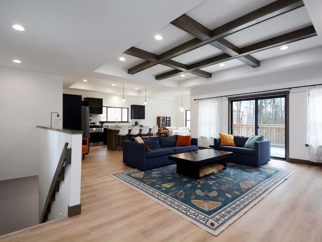 living area with beam ceiling, light wood-style flooring, and plenty of natural light
