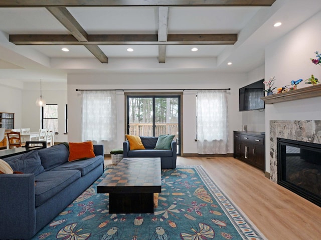 living area featuring beam ceiling, coffered ceiling, and light wood finished floors