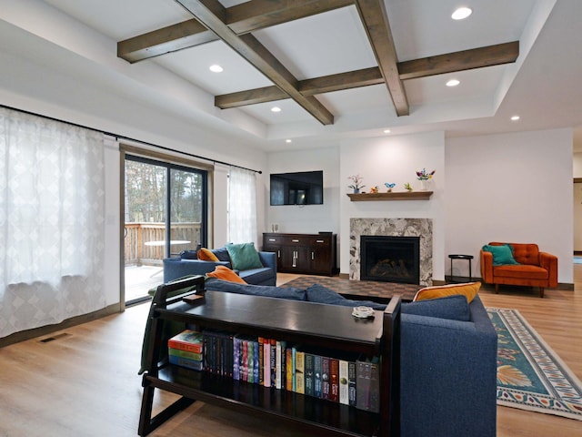 living room featuring visible vents, coffered ceiling, a premium fireplace, beam ceiling, and wood finished floors