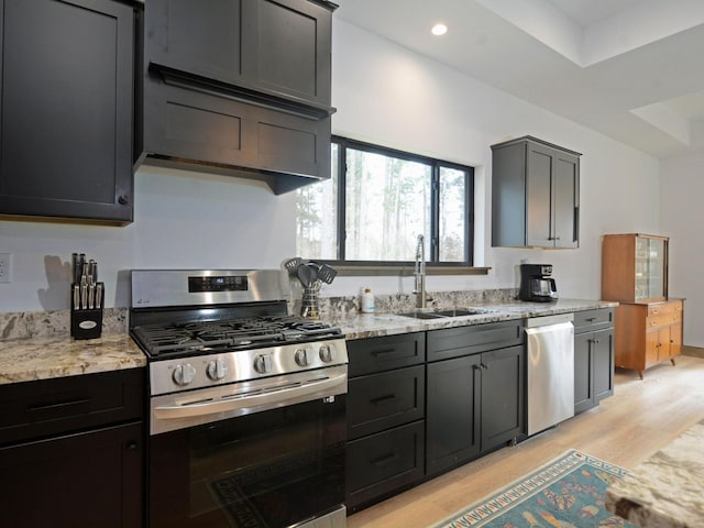 kitchen with recessed lighting, light stone countertops, a sink, light wood-type flooring, and appliances with stainless steel finishes