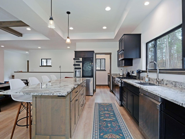 kitchen featuring a breakfast bar area, a sink, stainless steel appliances, and light wood-style floors