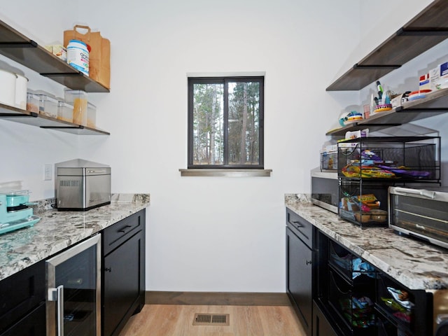 bar featuring a toaster, light wood finished floors, baseboards, visible vents, and wine cooler