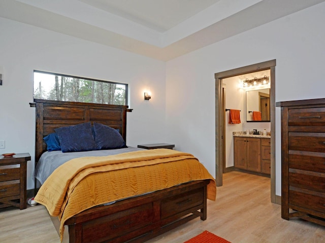 bedroom featuring connected bathroom and light wood-style floors