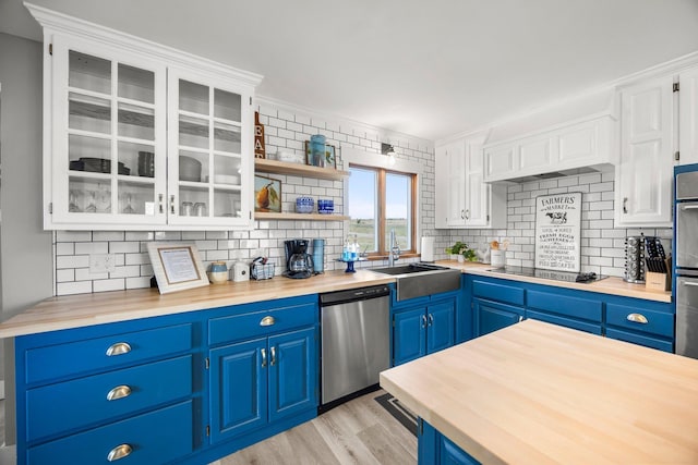 kitchen with a sink, wood counters, blue cabinetry, backsplash, and appliances with stainless steel finishes