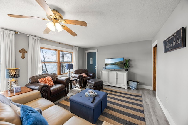 living room with a textured ceiling, a ceiling fan, wood finished floors, and baseboards