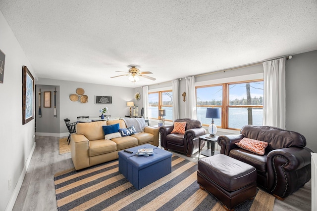 living room featuring wood finished floors, a ceiling fan, a textured ceiling, and a water view
