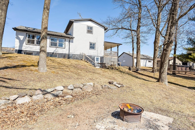 back of property featuring an outdoor fire pit and stairs