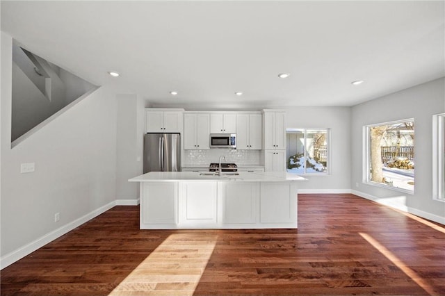 kitchen with white cabinetry, dark wood-type flooring, a kitchen island with sink, appliances with stainless steel finishes, and a sink