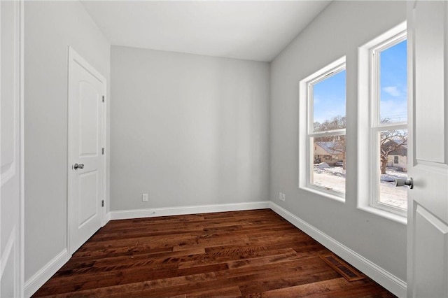 unfurnished room featuring visible vents, baseboards, and dark wood-style floors