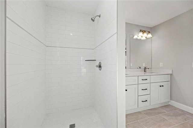 bathroom with a tile shower, vanity, and baseboards
