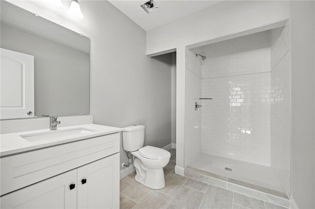 full bath featuring a tile shower, vanity, toilet, tile patterned floors, and baseboards