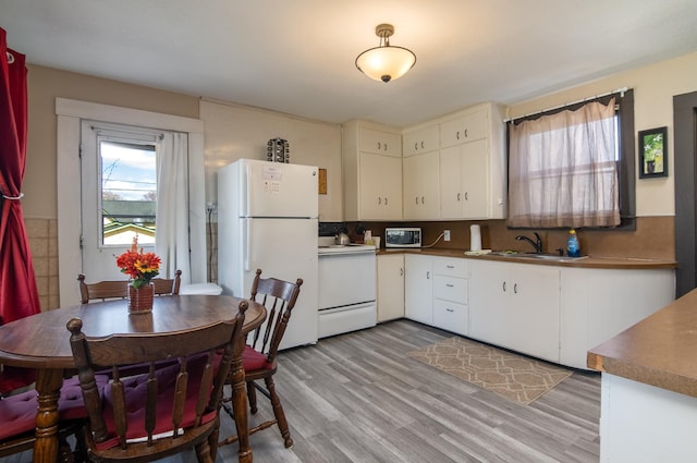 314 High St, Lake City, MN 55041 - kitchen featuring dark countertops, a sink, white appliances, light wood finished floors, and white cabinets