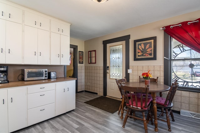 314 High St, Lake City, MN 55041 - kitchen with a wainscoted wall, a toaster, visible vents, tile walls, and light wood-type flooring