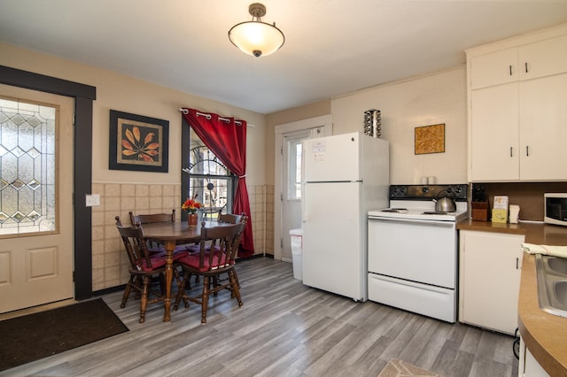 314 High St, Lake City, MN 55041 - kitchen with light wood-style floors, tile walls, white cabinetry, and white appliances