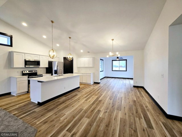 kitchen with stainless steel appliances, an inviting chandelier, vaulted ceiling, light wood-style flooring, and white cabinetry