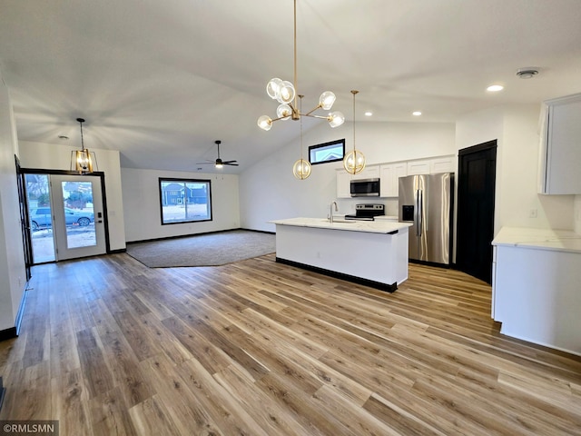 kitchen with open floor plan, vaulted ceiling, light wood-style floors, light countertops, and appliances with stainless steel finishes